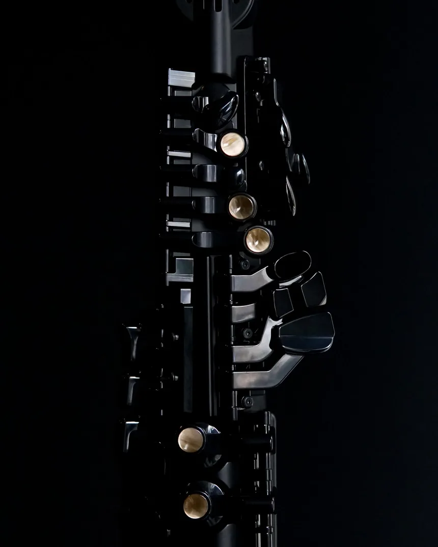 Detalle de las llaves y anillos de un clarinete de madera sobre fondo oscuro